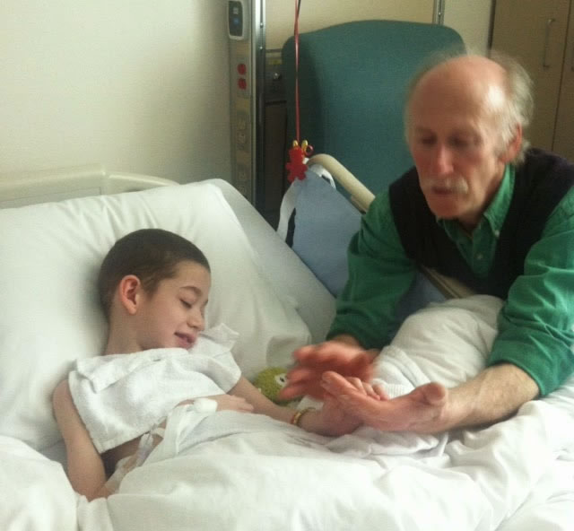 Jackson at Aidan's hospital bedside, Aidan with a slight smile